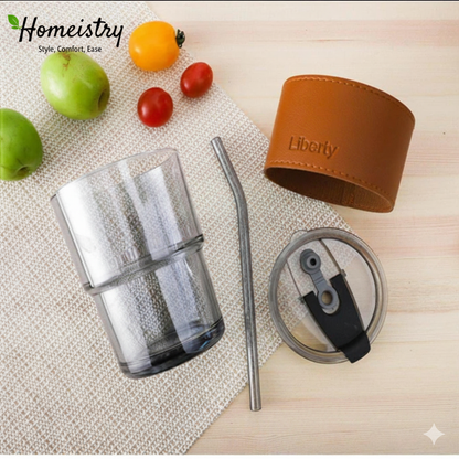 Clear drink container with brown sleeve, straw, and lid on a wooden surface with fruits.