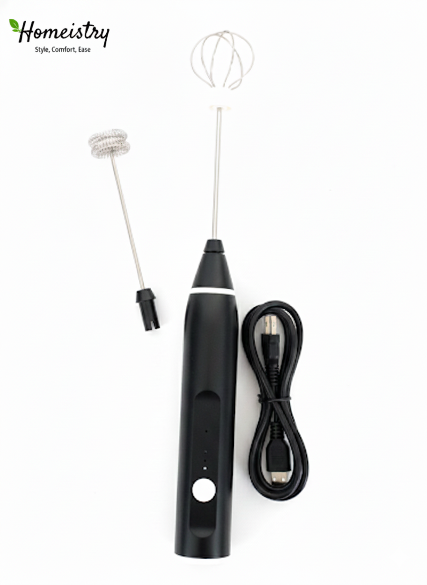 Flat lay of Homeistry black electric milk frother with balloon whisk attachment and USB charging cable on a white background.
