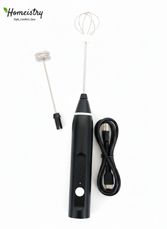 Flat lay of Homeistry black electric milk frother with balloon whisk attachment and USB charging cable on a white background.