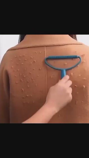 Demonstration of blue manual lint remover scraping fuzz off a beige wool coat.